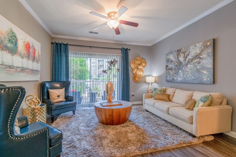A living room with a black leather chair, a wooden coffee table, a white couch, and a painting on the wall.