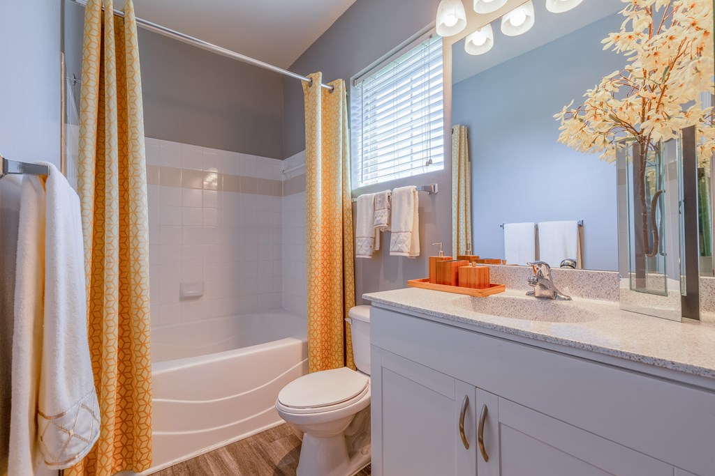 A white toilet sits in a bathroom with a white sink and a white bathtub.