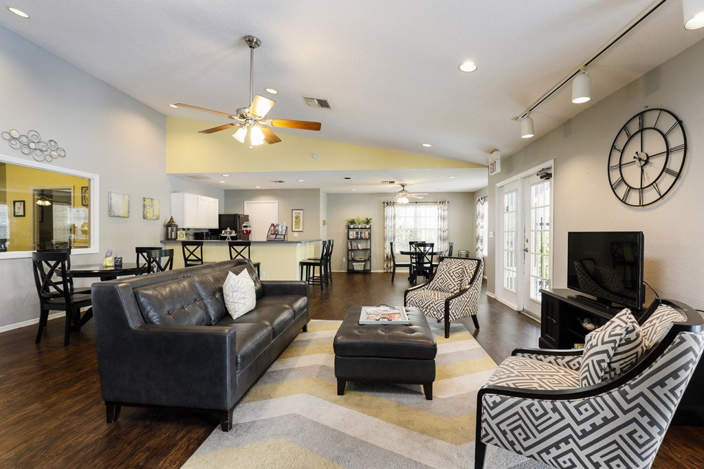 Clubhouse lounge with couches, chairs, coffee table, tiled flooring, and multi speed ceiling fan