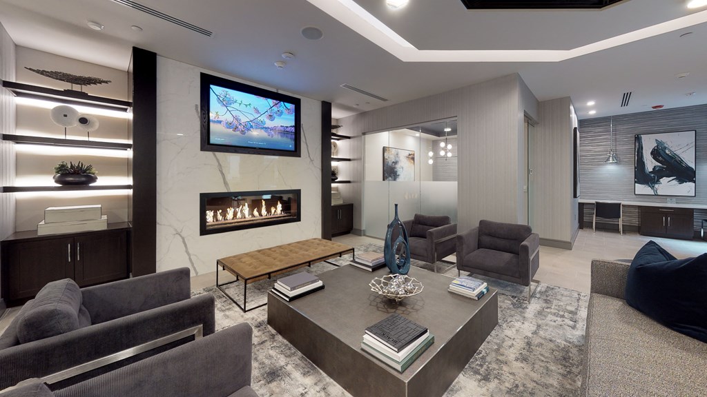 Resident clubhouse common area facing a fireplace and couches next to a television