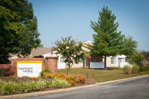 A sign that says Coachman's Landing is in front of some houses.