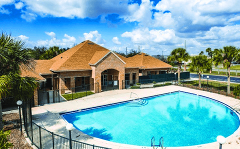 A swimming pool in front of a house with a fence around it.