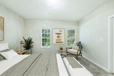 A bedroom with a large bed and a chair.