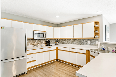 A kitchen with a refrigerator, microwave, and wooden cabinets.