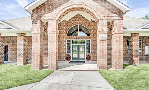 A brick building with a green door and windows on either side.