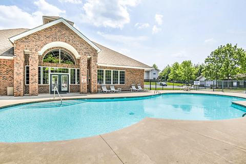 Leasing Office Exterior with Swimming Pool and Sun Deck with Lounge Chairs Near Tree-line