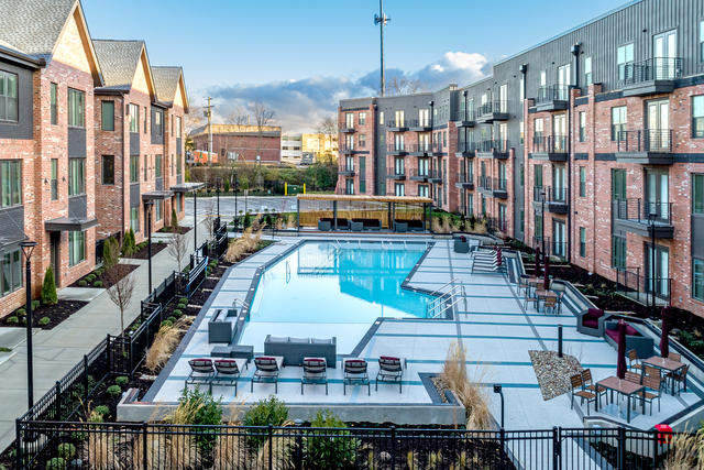 a large swimming pool with tables and chairs in front of a building