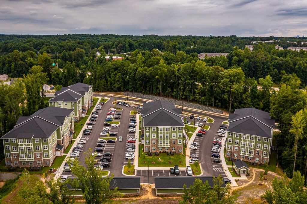 An aerial view of a parking lot surrounded by buildings and trees. at Foxwood Apartments, Raleigh-Durham