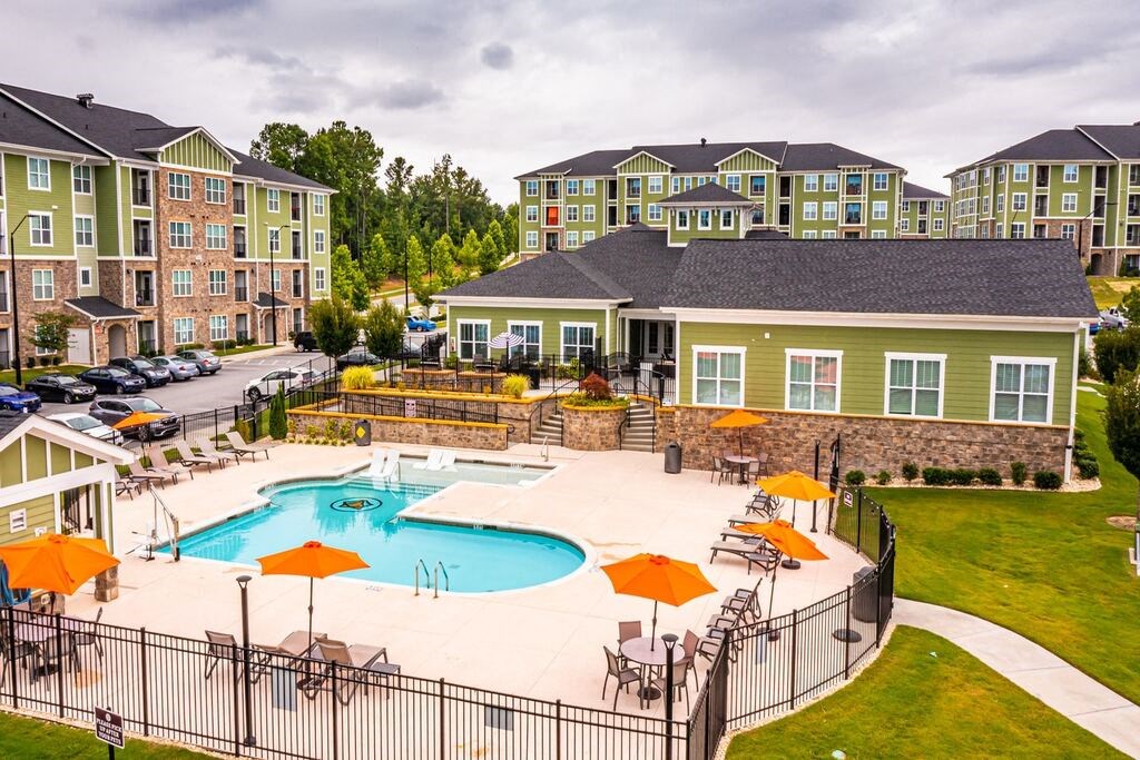 A pool surrounded by a black fence and orange umbrellas at Foxwood Apartments, Raleigh-Durham, 27616