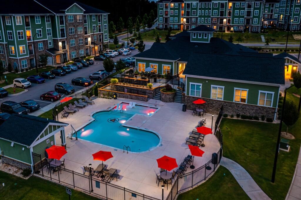 A pool surrounded by a black fence and red umbrellas at Foxwood Apartments, Raleigh-Durham, NC