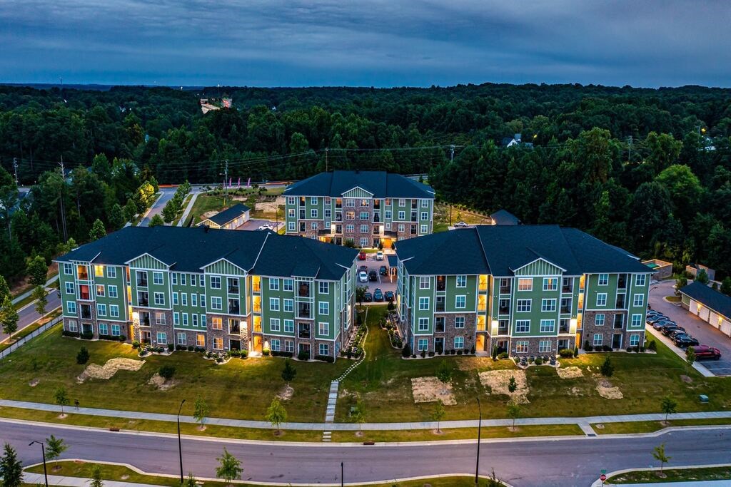 A large apartment complex with multiple buildings and lit windows at Foxwood Apartments, Raleigh-Durham