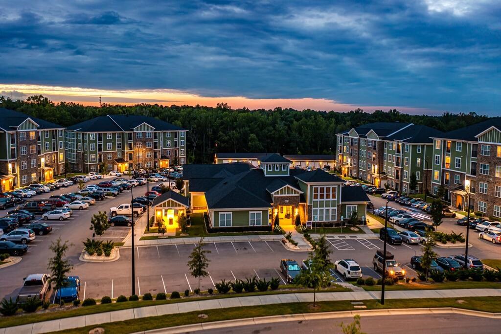 A parking lot with cars and a building with a lit up number 6 at Foxwood Apartments, North Carolina, 27616