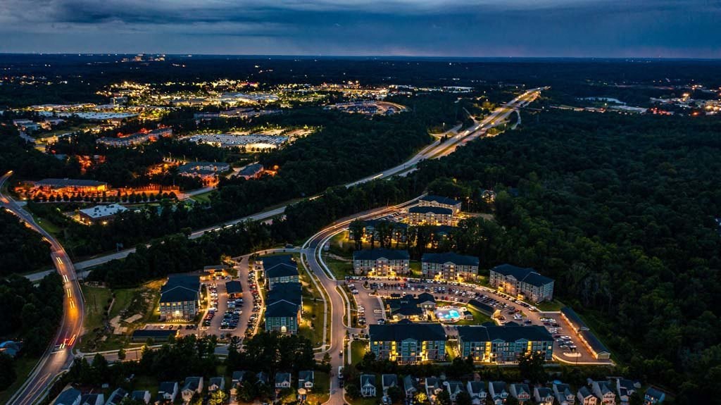 A nighttime aerial view of a residential area with a lit-up road and houses at Foxwood Apartments, Raleigh-Durham, North Carolina