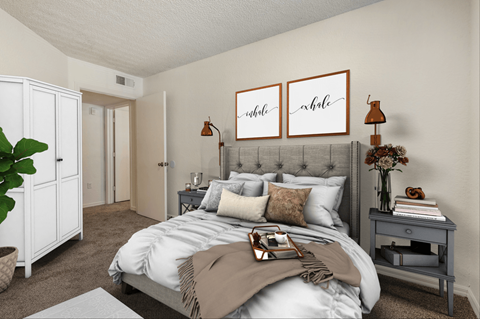A bedroom with a large bed and a grey nightstand.