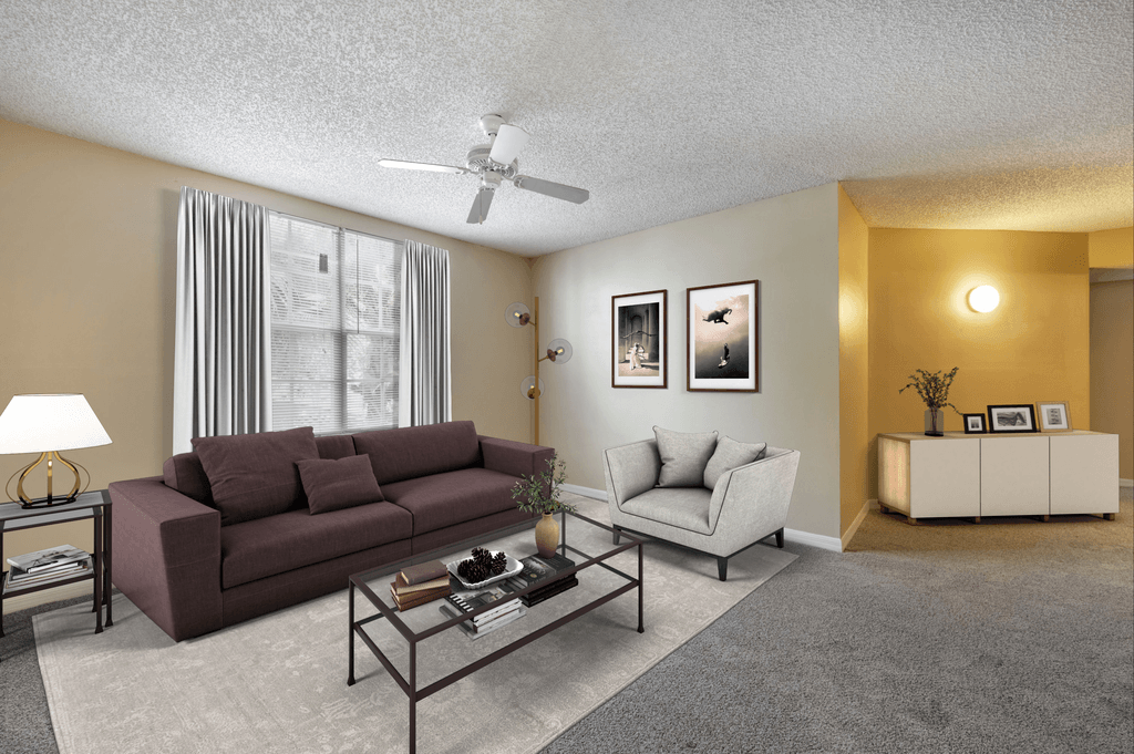 Virtually staged living room with tan carpeted flooring,  arge window with white blinds and a white multi-speed ceiling fan
