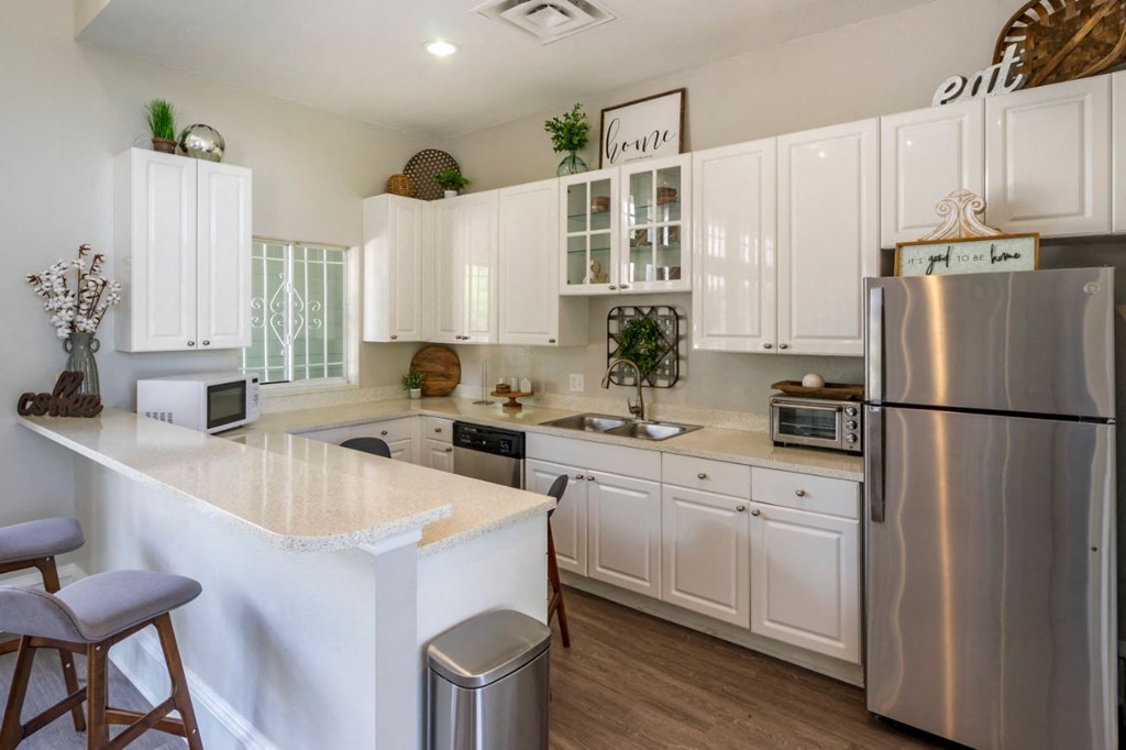 Clubhouse kitchen with stainless steel appliances, white cabinetry, and hardwood flooring