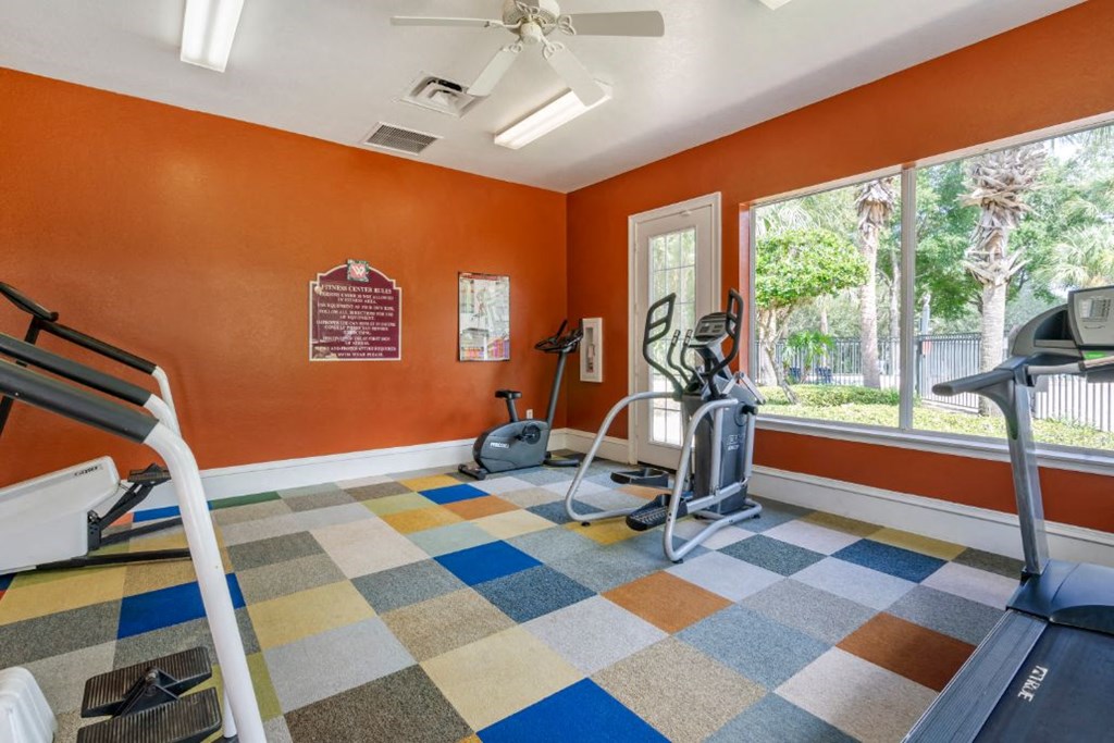 Fitness center with cardio equipment and large windows for natural lighting