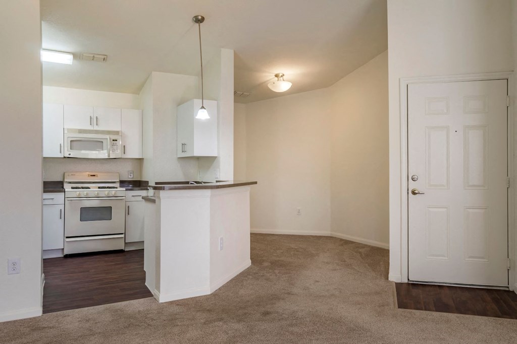 Fully equipped kitchen with white appliances and dining room with carpet flooring
