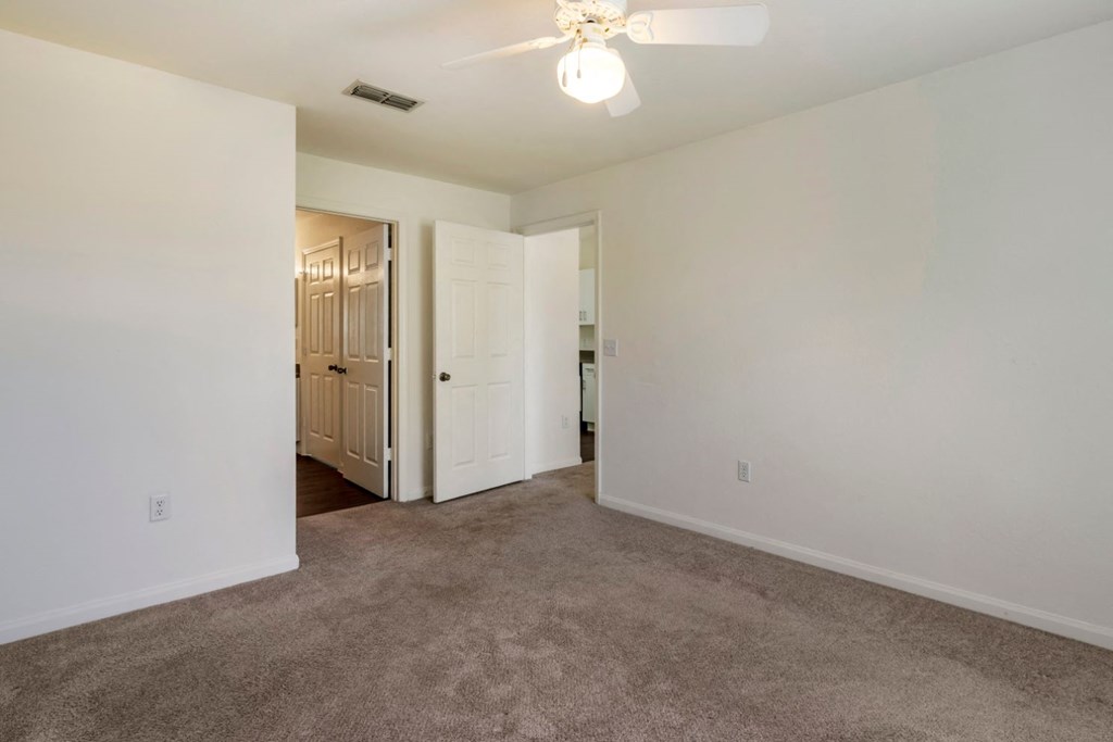 Bedroom with carpet flooring, multi speed ceiling fan, and in-suite bathroom