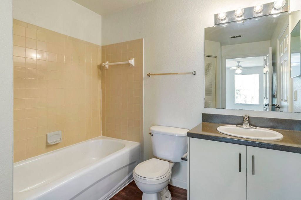 Bathroom with hardwood style flooring, large mirror, and vanity lighting