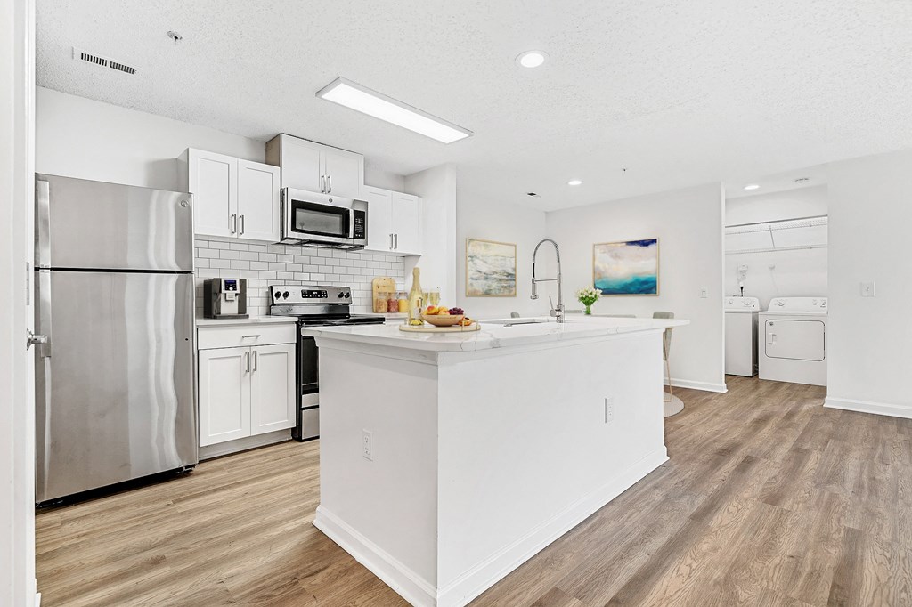 A modern kitchen with white appliances and a wooden floor. at The Grayson Apartment Homes, Charlotte