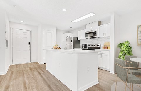 A kitchen with white cabinets and a wooden floor.