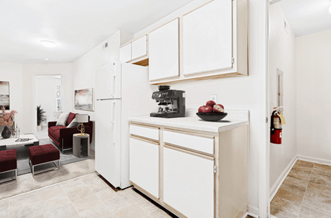 A kitchen with white cabinets and a red chair.