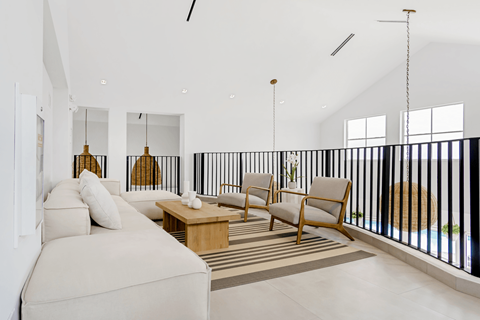 A living room with a white couch and a black railing.