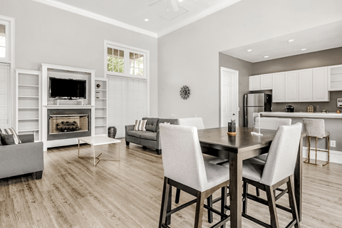 Clubhouse lounge with cafe style seating, hardwood style flooring, couches, chairs, fire place and wall mounted television