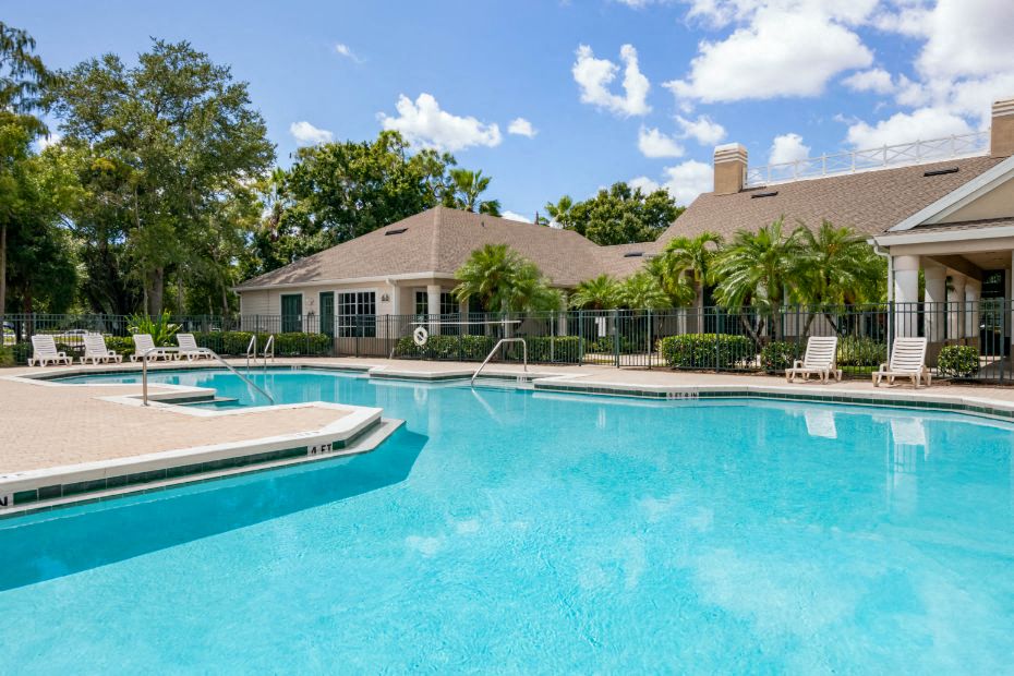 Leasing Office Exterior with Swimming Pool and Sun Deck with Lounge Chairs with Trees and Building Exteriors in the Background