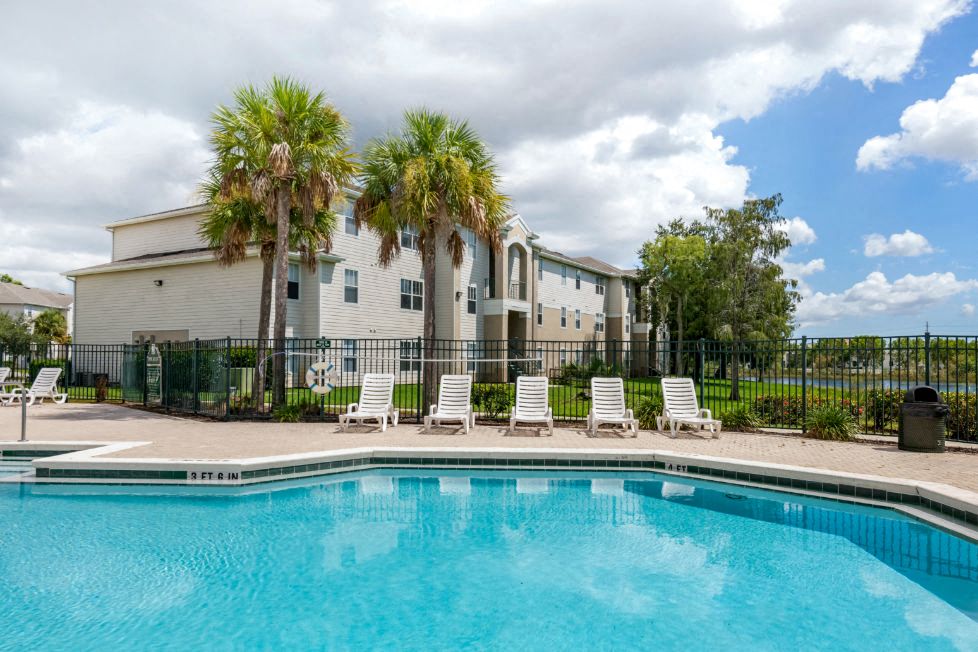 Swimming Pool and Sun Deck with Lounge Chairs with Trees and Building Exteriors in the Background