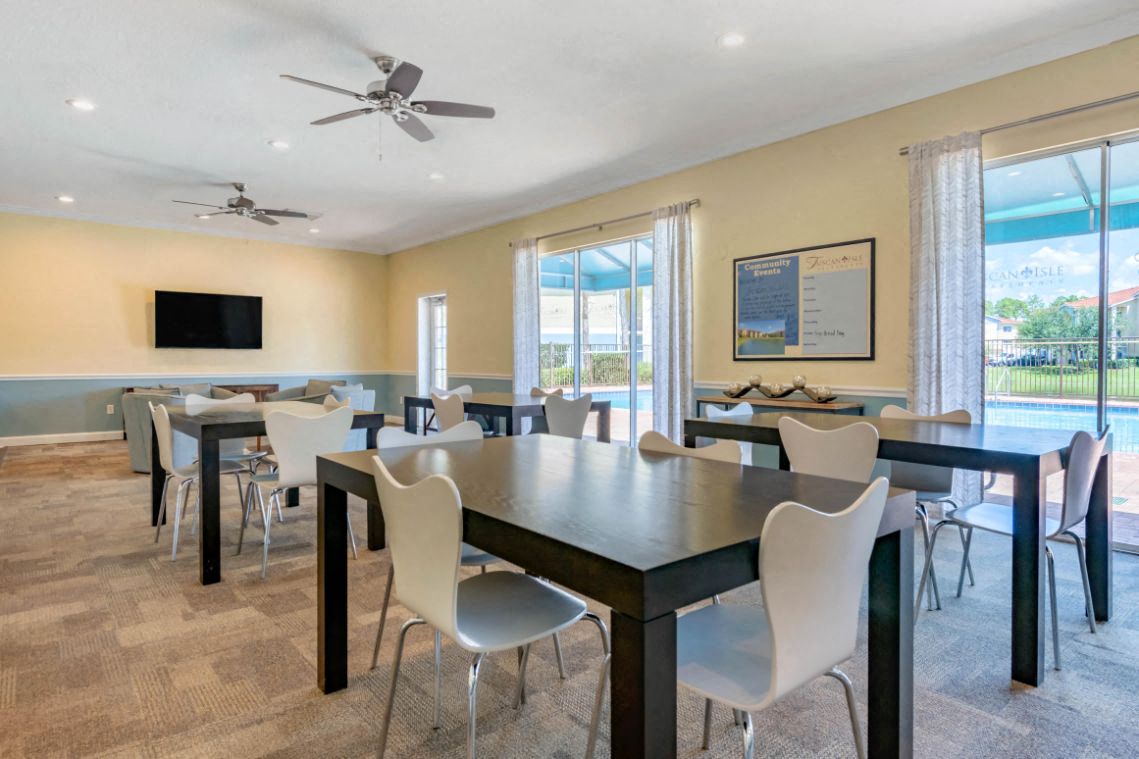 Clubhouse with Large Windows Black Tables with White Chairs Mounted TV and Ceiling Fans