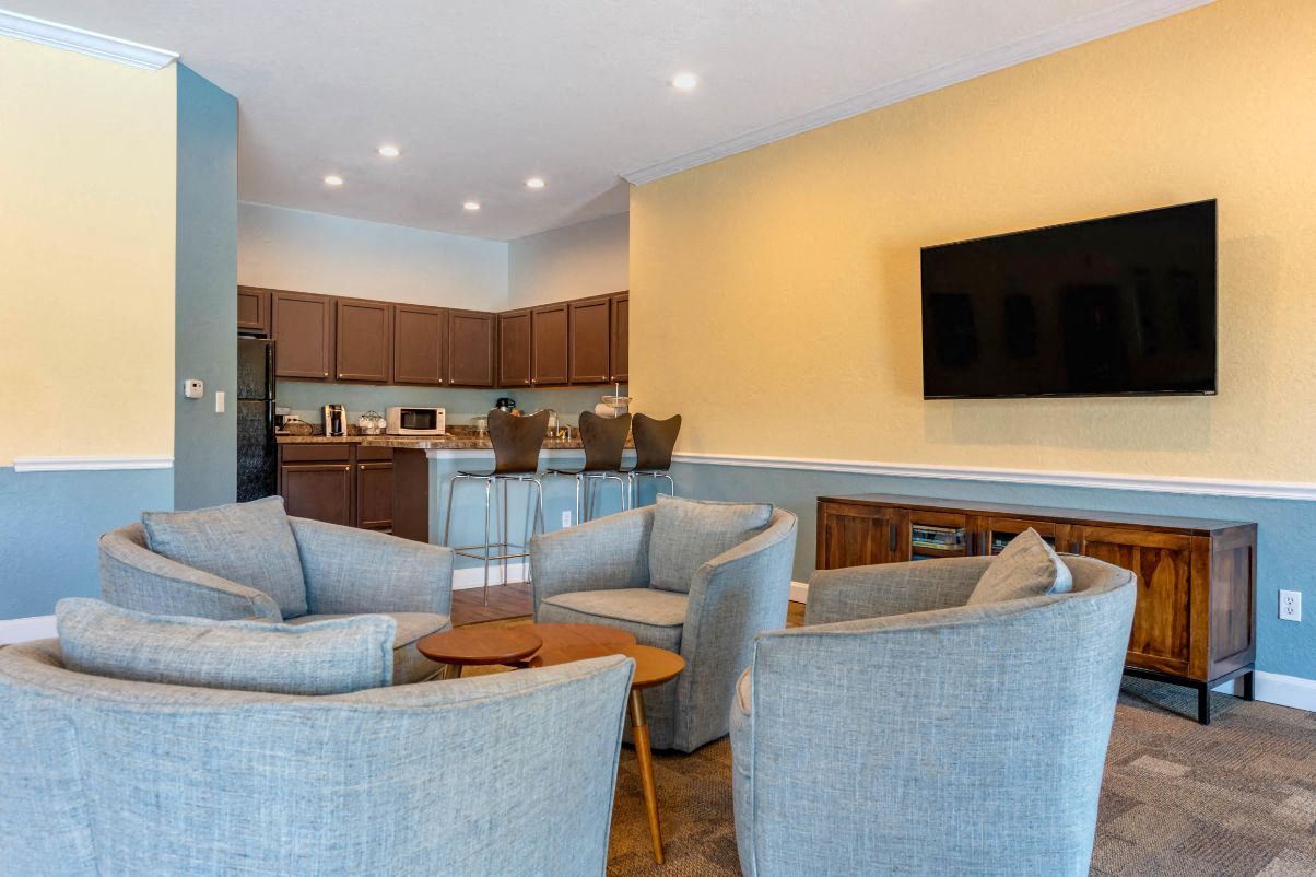 A living room with grey chairs and a television on the wall.