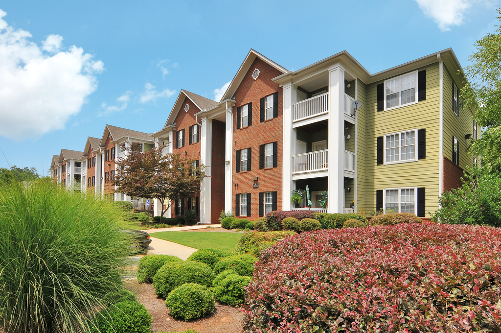 Exterior of apartment with a grass area and flower bed by the building
