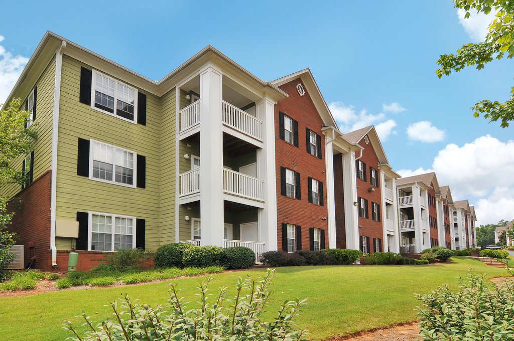 Exterior of apartment with a grass area and flower bed by the building