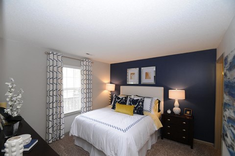 A bedroom with a white bed and a window with curtains.