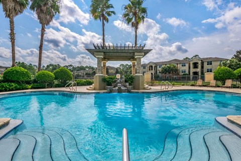 Resort style swimming pool with sundeck and lounge seating surrounded by native landscaping