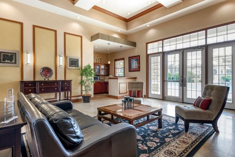 Clubhouse lounge with couch, chair, coffee table, high ceilings, and large windows for natural lighting