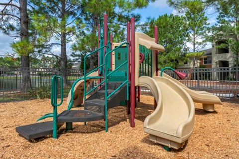 Outdoor playground with seesaw, bench seating, surrounded by native landscaping