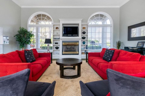 A living room with red couches and a fireplace.