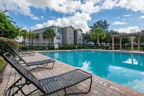Swimming pool with lounge seating and apartment building exterior in the background