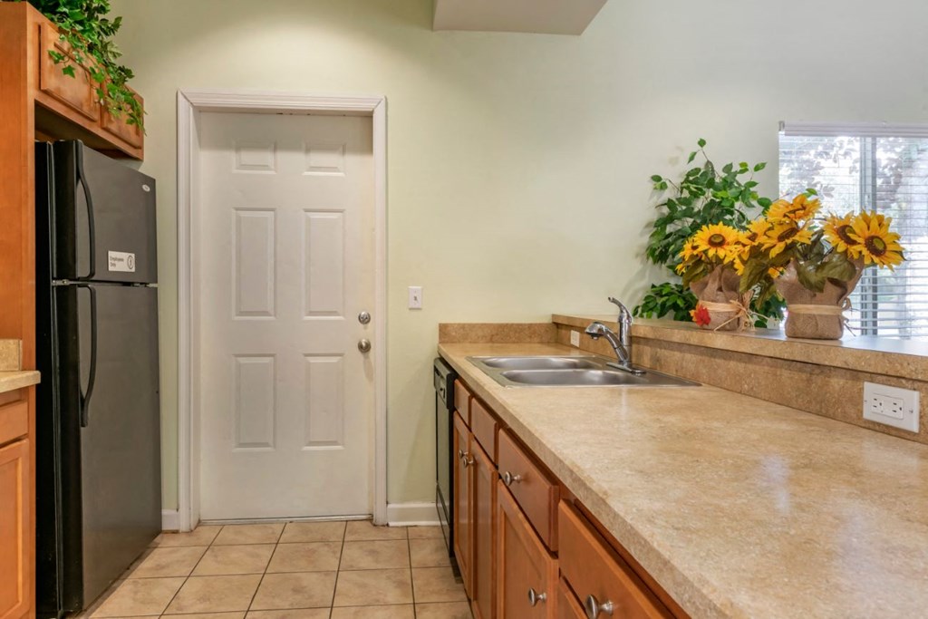 Clubhouse kitchen with tile flooring, black appliances, and double basin sink