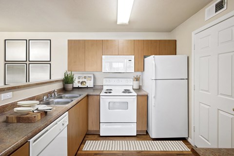 A white kitchen with wooden cabinets and a white fridge.