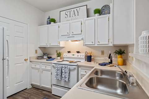 A kitchen with white cabinets and a stainless steel sink.
