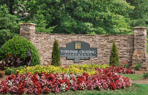 a sign for the town park closing apartments on a stone wall with colorful flowers