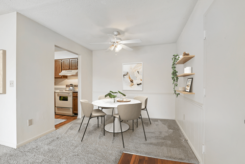 a dining area with a white table and chairs and a ceiling fan