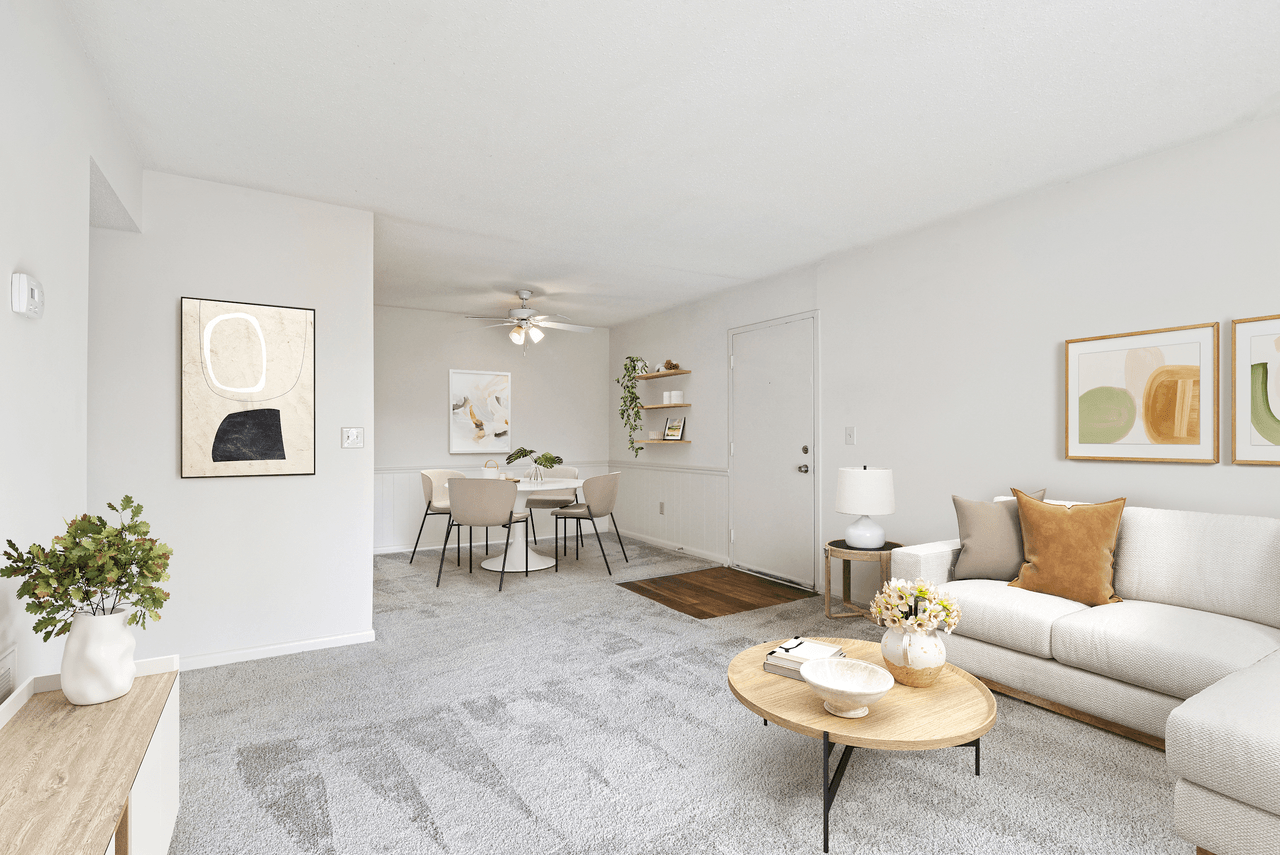 A living room with a grey carpet and a white couch.