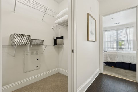 A white bedroom with a bed in the other room.