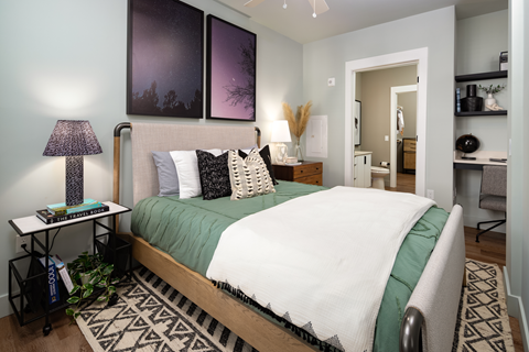 A bedroom with a bed, nightstand, and a lamp.