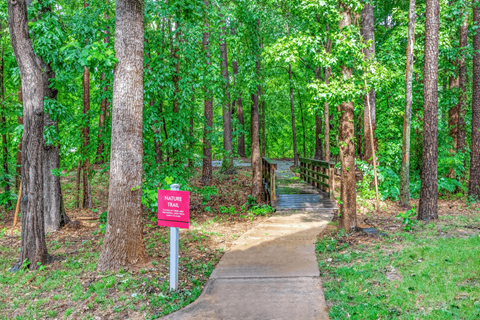 a path through the woods with a red sign on the side of the path at Elan at Mallard Creek Apartment Homes, Charlotte, 28269